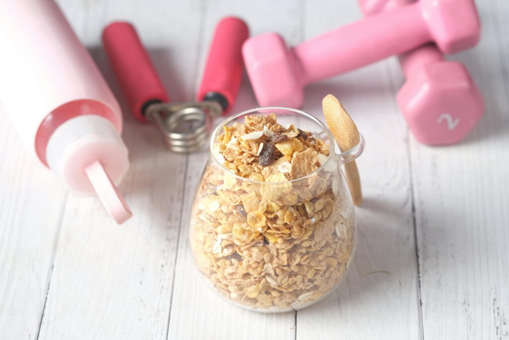 A glass jar of granola with pink dumbbells and a water bottle for a fitness-inspired healthy meal.